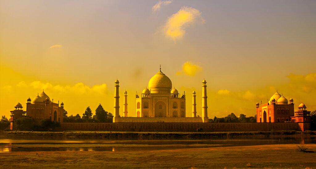 Taj Mahal at sunset seen from Mehtab Bagh with orange sky and river reflection, perfect for evening photography.